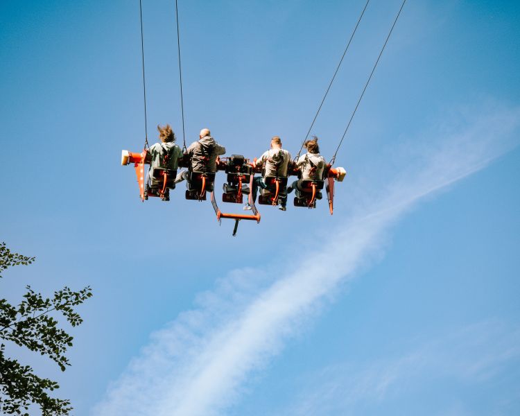 people on the zip world skyride in wales against the blue sky