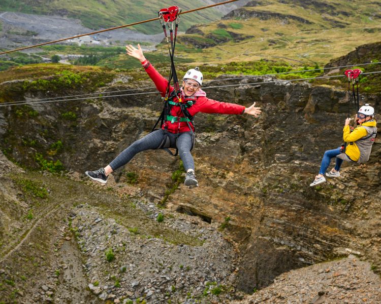 view of two people going down the zip lines at zip world titan in wales