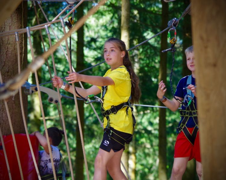 young girl on the zip world tree hoppers course in the trees