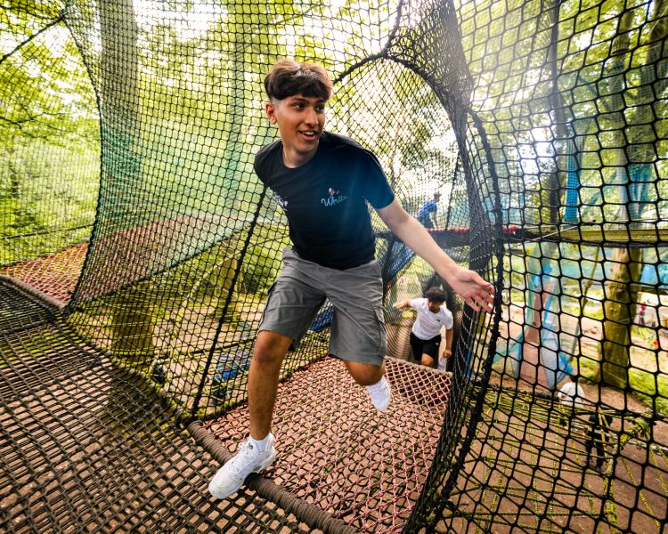 young boy running through the nets at zip world treetop nets