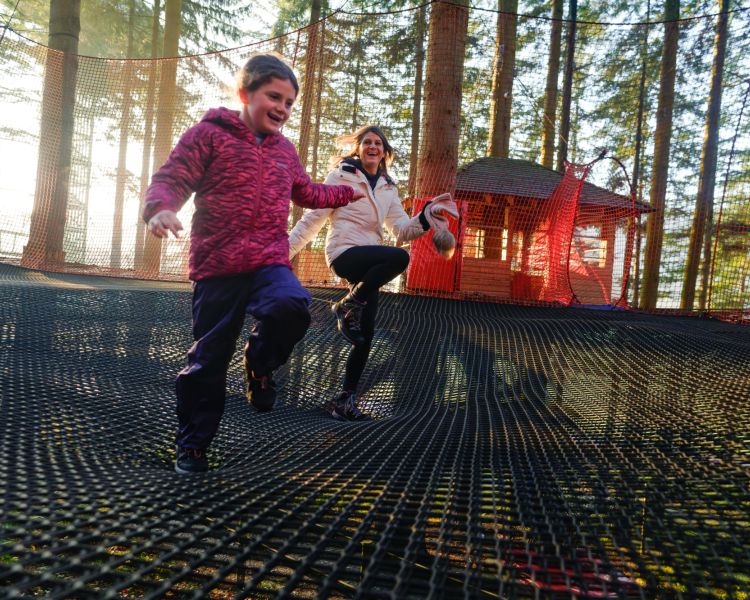 woman and child jumping on the zip world treetop nets