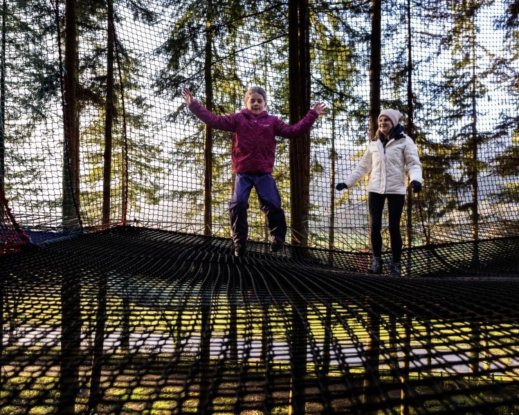 two people jumping on the nets at zip world treetop nets