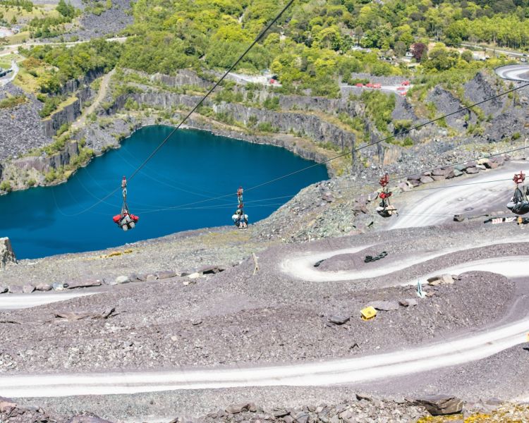 view of people on the zip lines at zip world velocity in wales going over the quarry lake