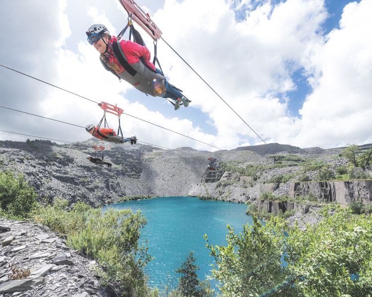 people on the zip lines going over the quarry lake at zip world velocity in wales