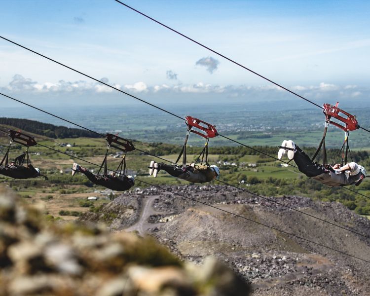 people on the zip lines going over the quarry lake at zip world velocity in wales
