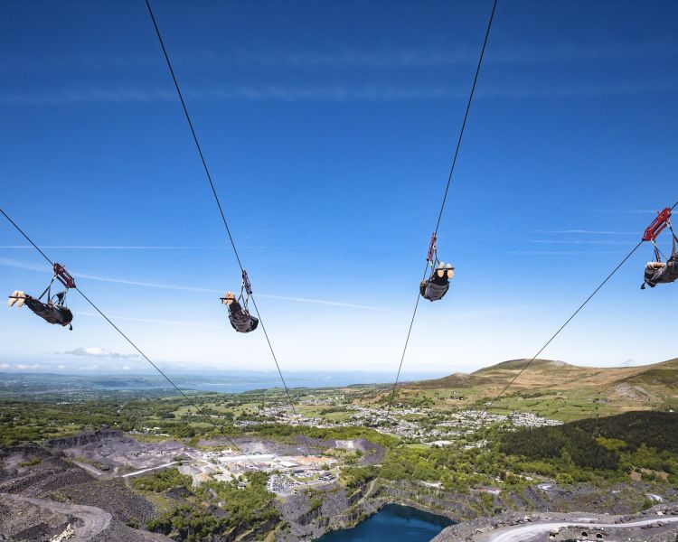 people on the zip lines going over the quarry lake at zip world velocity in wales