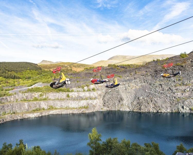 people on the zip lines going over the quarry lake at zip world velocity in wales