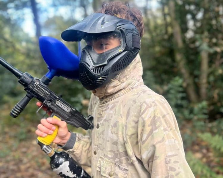 Young boy in a helmet holding a paintball gun