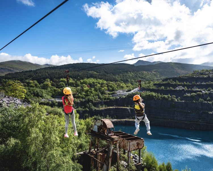 two young girls on the zip world quarry flyer zip line going over the quarry
