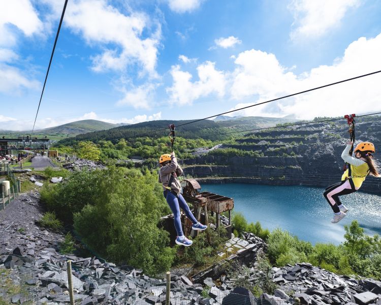 two young girls on the zip world quarry flyer zip line going over the quarry