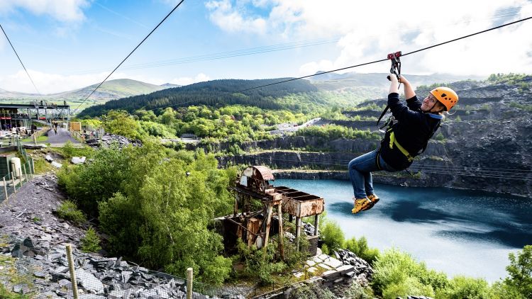 young woman on the zip world quarry flyer zip line going over the quarry