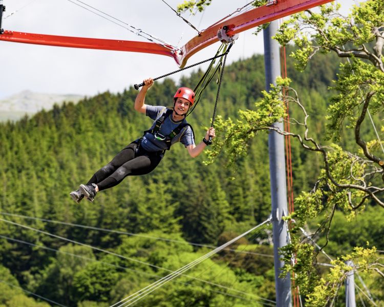 woman flying around the zip world aero explorer overlooking woodland