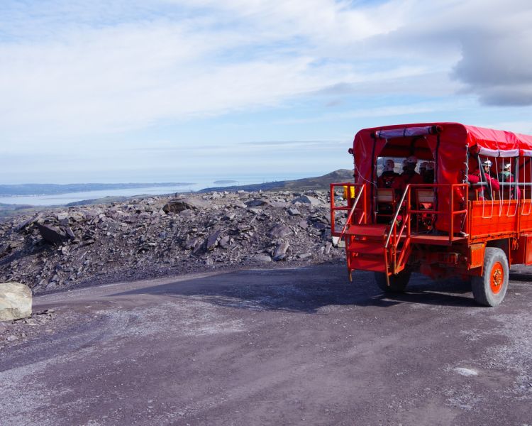 view of the red ex army truck that you can tour penrnyn slate quarry in overlooking hills of slate