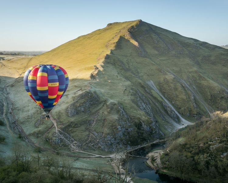 a multi coloured hot air balloon flying over tutu peaks
