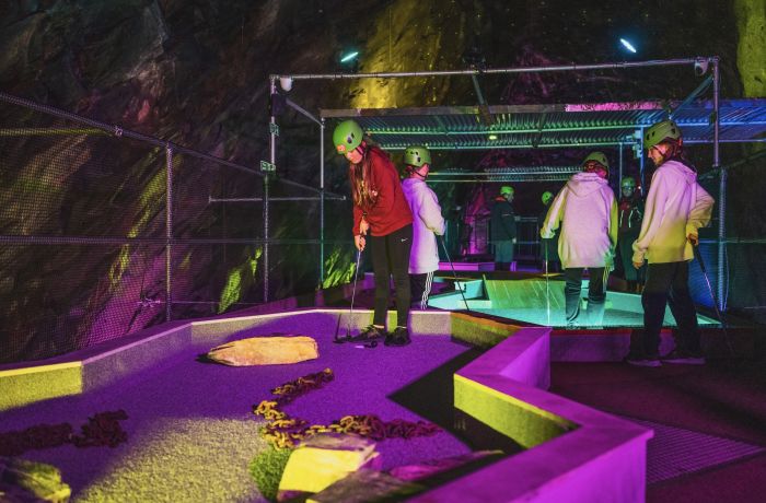 young people playing golf in an old slate mine at zip world underground golf