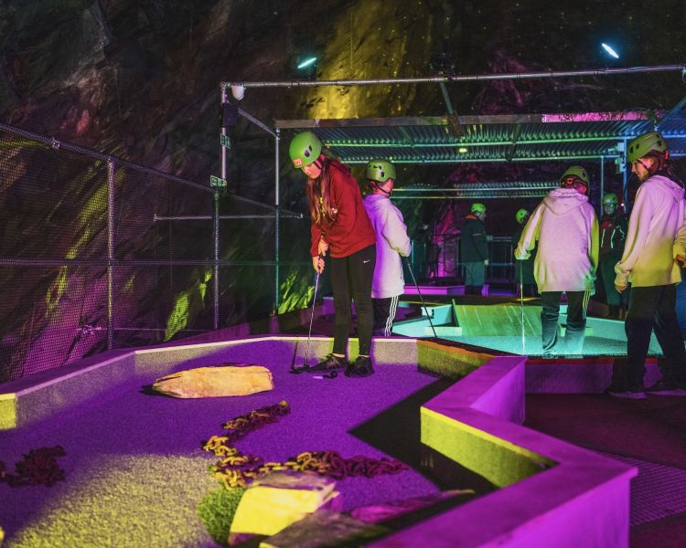 young people playing golf in an old slate mine at zip world underground golf