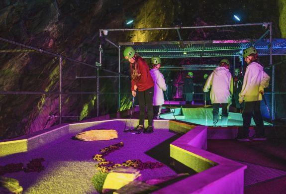 young people playing golf in an old slate mine at zip world underground golf