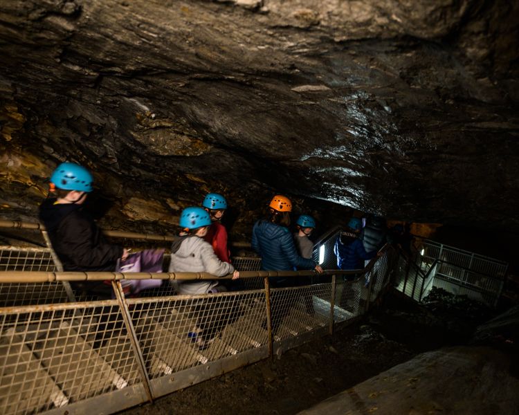 group of people descending down a staircase into the underground caverns on the zip world llechwedd deep mine tour