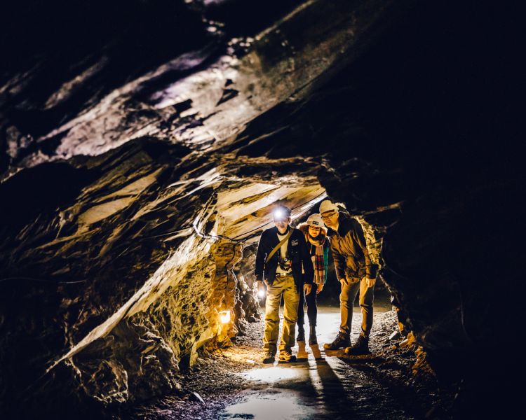 people walking through a tunnel on the zip world llechwedd deep mine tour