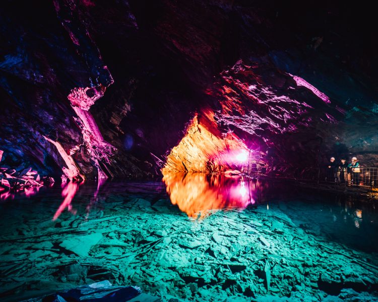 the underground lake lit up in green and pink lighting seen on the zip world llechwedd deep mine tour
