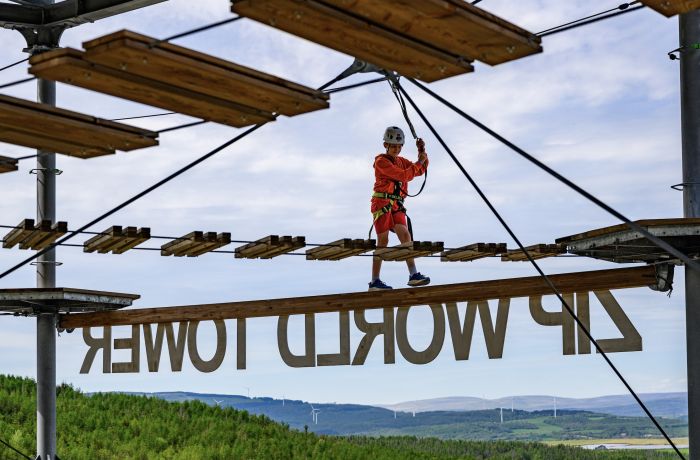 a boy walking along a balance beam on the zip world tower climber in south wales