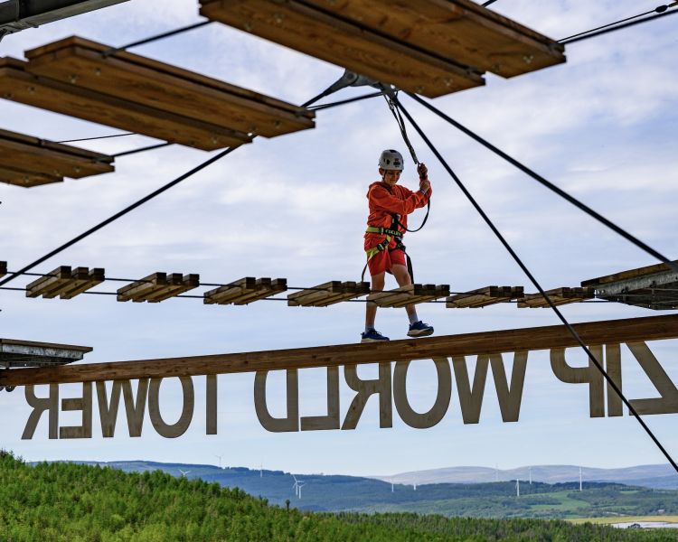 a boy walking along a balance beam on the zip world tower climber in south wales