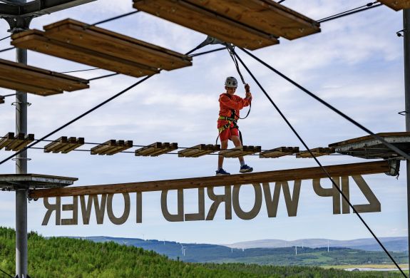 a boy walking along a balance beam on the zip world tower climber in south wales