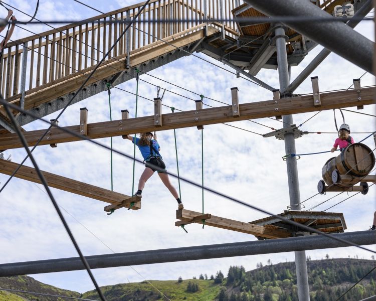 young girl stretching to reach the next platform on the zip world tower climber in south wales