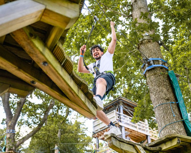 view looking up at a man on the zip world full trek manchester treetop obstacle course