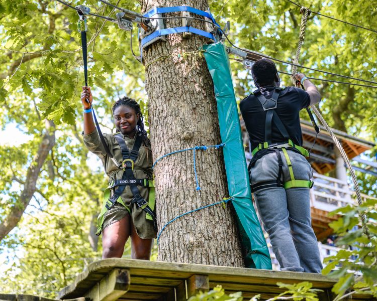 two people on a platform between obstacles on the zip world full trek manchester treetop obstacle course