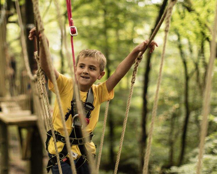 boy crossing a bridge on the zip world mini trek manchester course