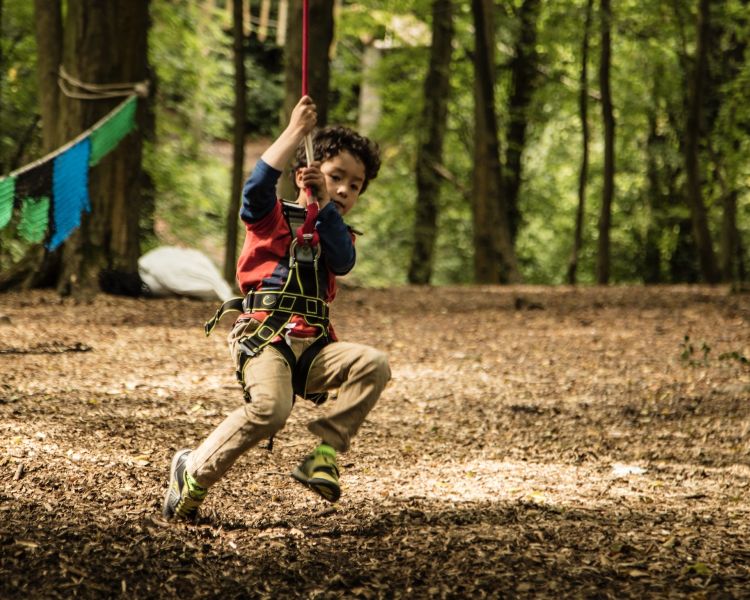 young boy landing on the ground from a zip line on the zip world mini trek manchester course
