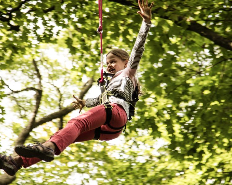 young girl hanging on the zip line on the zip world mini trek manchester course