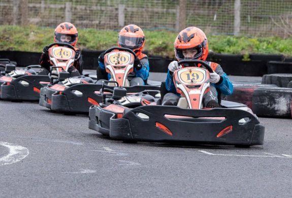 three people in a go kart race on a track