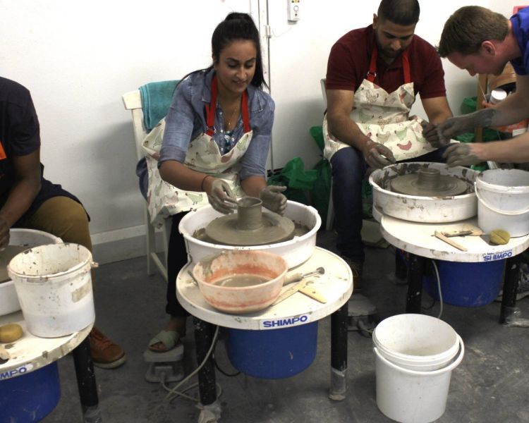 people at potters wheels on a pottery introduction experience