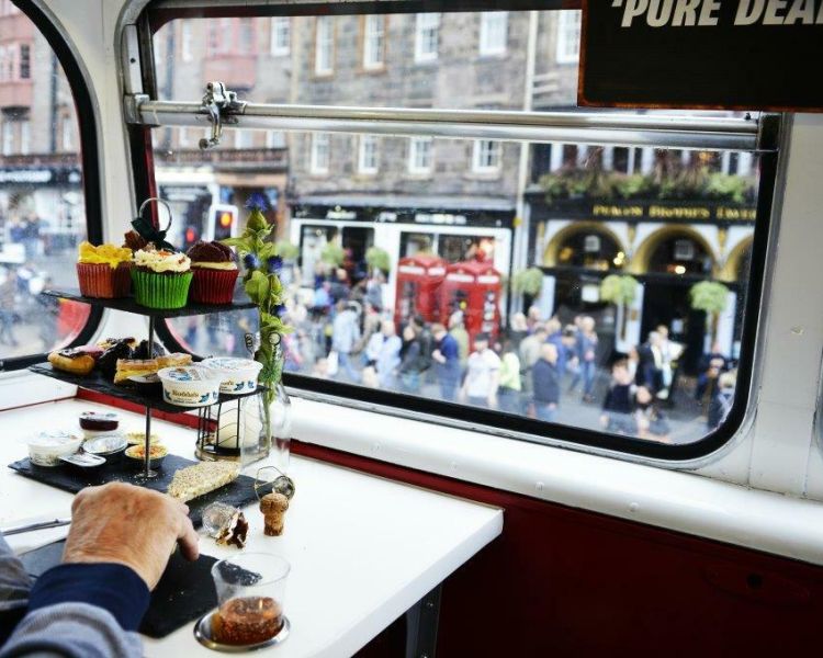 person enjoying afternoon tea looking through the windows on the red bus bistro afternoon tea tour