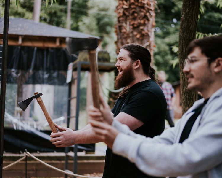 two men holding axes ready to throw them on an axe throwing experience