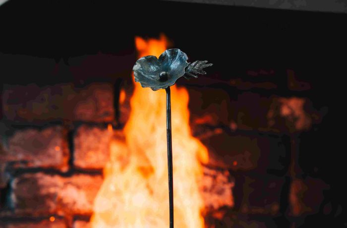 an iron poppy in front of an open fire made on a blacksmith poppy making experience