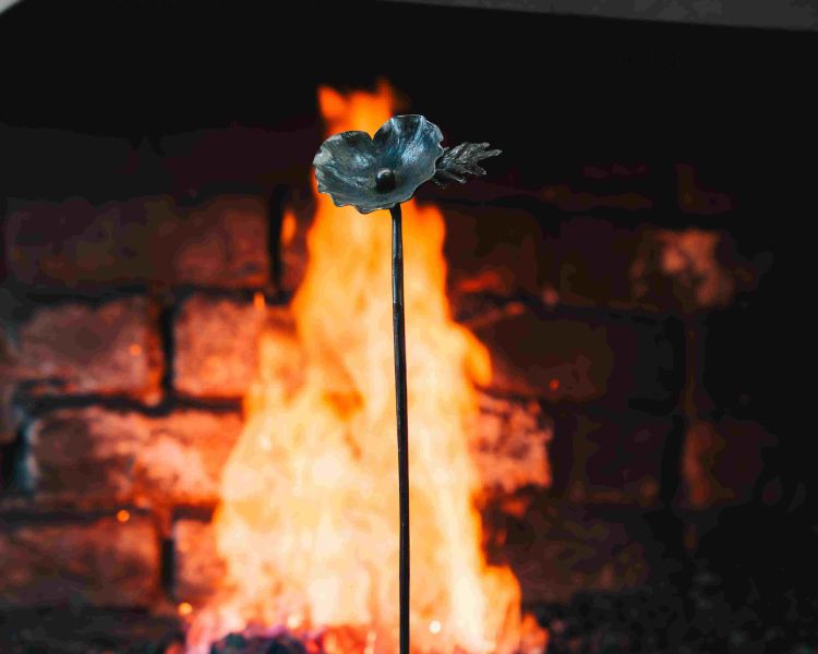 an iron poppy in front of an open fire made on a blacksmith poppy making experience