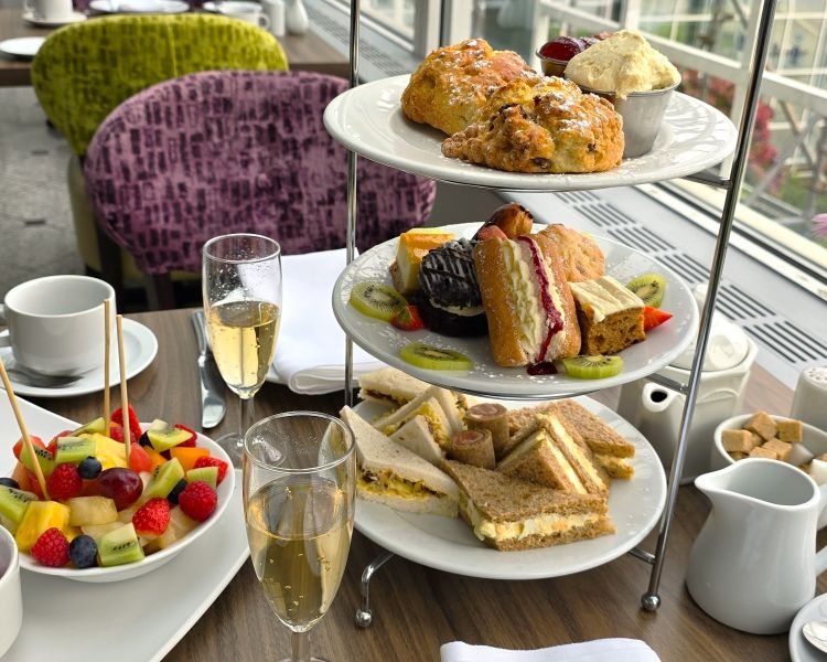 a deluxe afternoon tea with glasses of prosecco laid out on a table