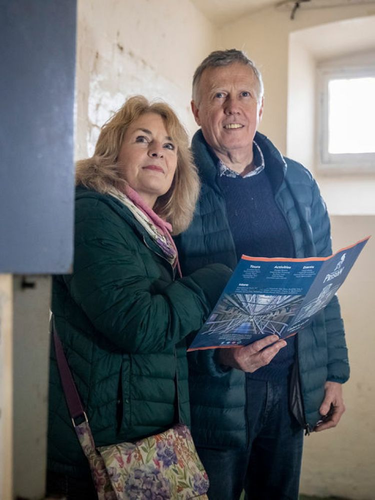 man and woman holding a guide in a prison cell on a self guided tour of a former prison experience day