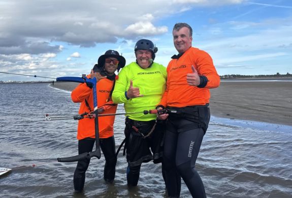 man standing on beach with two instructors on a kitesurfing experience