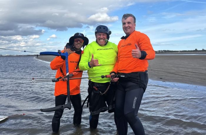 man standing on beach with two instructors on a kitesurfing experience