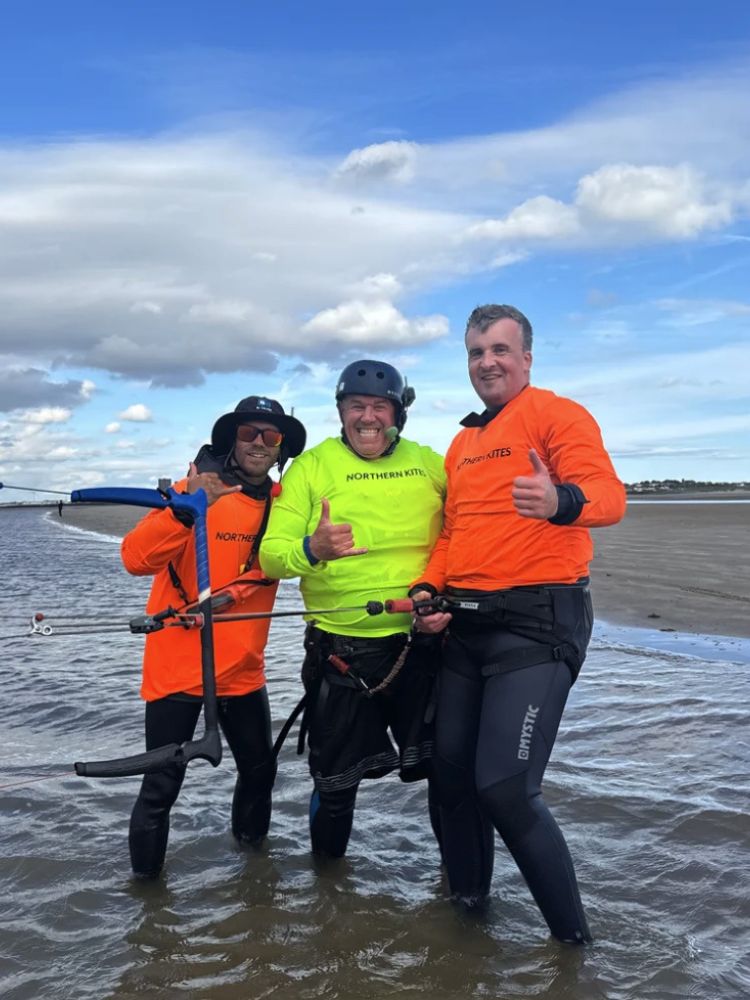 man standing on beach with two instructors on a kitesurfing experience