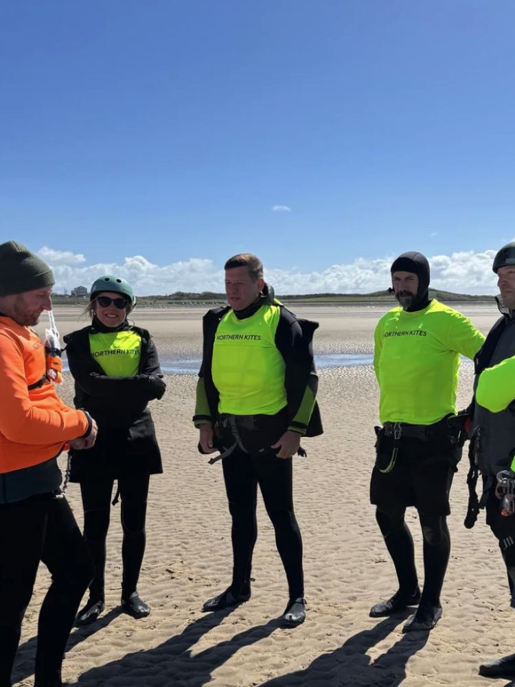 a group of students listening to an instructor on the beach on a land kitesurfing lesson