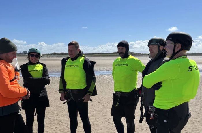 a group of students listening to an instructor on the beach on a land kitesurfing lesson
