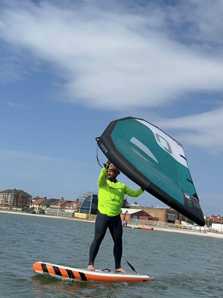 man wingsurfing on the water on a learn to wingsurf experience