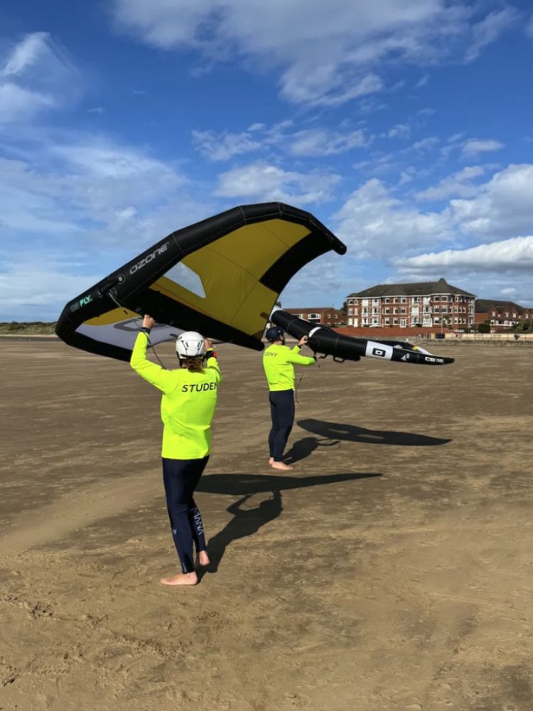two students learning winghandling skills on the beach on a learn to wingsurf experience