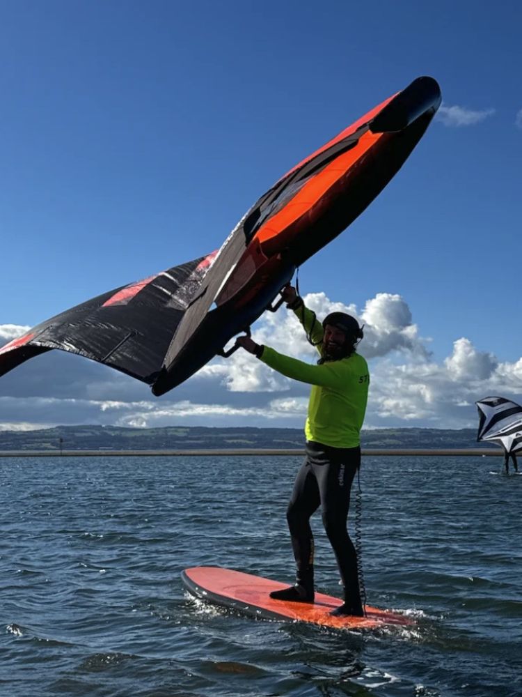 man wingsurfing on the water on a learn to wingsurf experience