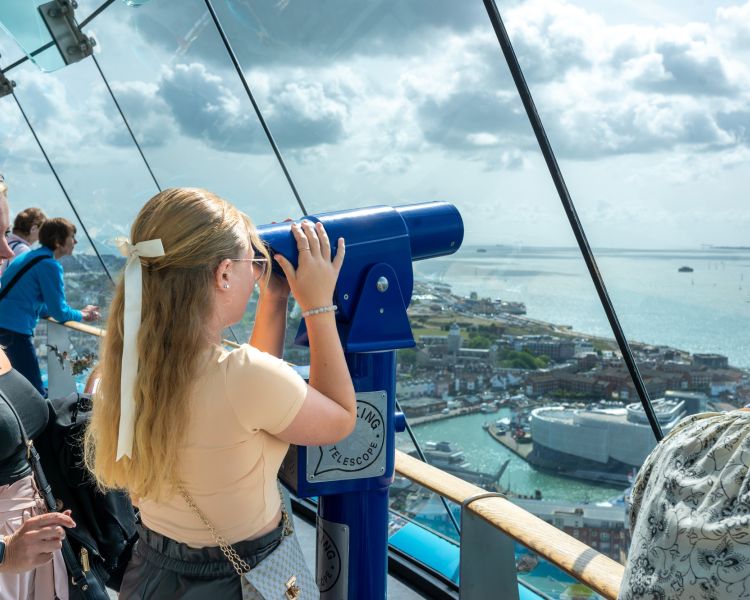 A girl uses binoculars to look out over Portsmouth